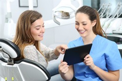 Dental assistant showing patient image on tablet