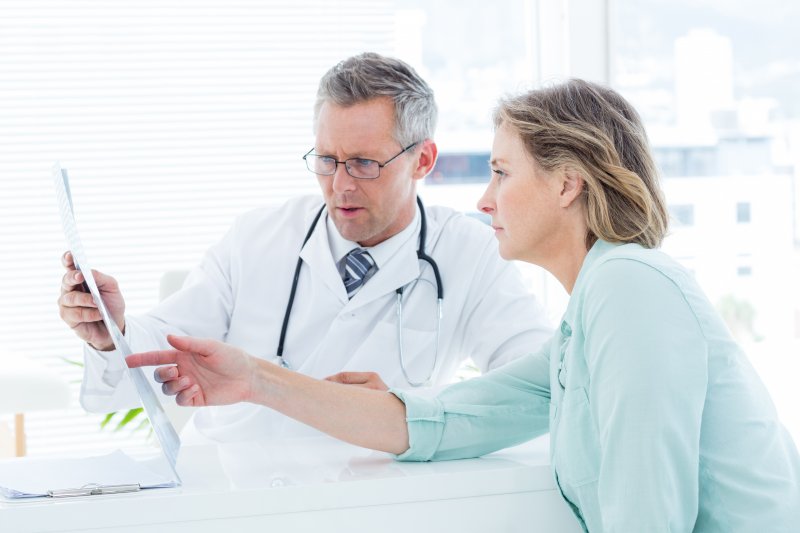 A doctor holding an x-ray while talking to his patient